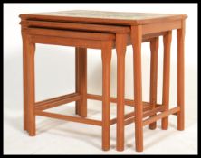 A vintage retro mid 20th century nest of three teak tables having a tiled painted green sunburst
