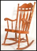 An antique style 20th century pine large rocking chair raised on shaped bow rockers with turned back