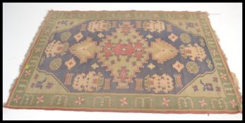 A vintage early 20th century floor carpet rug having a green and blue ground with geometric panels