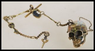 A vintage 20th century brass Albert watch chain with a skull locket having a hinged jaw and skeleton