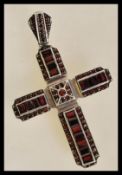A sterling silver 925 large cross pendant set with faceted emerald cut and circular garnet stones.
