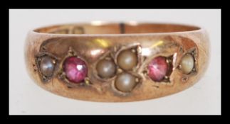 A 19th century Victorian 9ct gold ring with seed pearl inlay and two in set red stones. The item