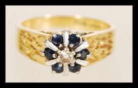 A contemporary hallmarked 18ct gold ring with six inlaid sapphires surrounding a central white stone