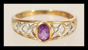 A hallmarked 9ct gold ring having a pierced cross design to the shank with an inset purple stone,