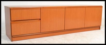 A retro 20th Century teak wood Danish inspired low sideboard having an arrangement of cupboard and
