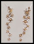 A pair of vintage retro 20th century drop earrings with floral detailing in yellow and white metal.