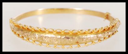 An Edwardian hallmarked Birmingham 9ct gold bangle bracelet with a hinge clasp and safety chain