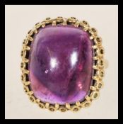 A hallmarked 9ct gold ring with a large inset purple stone having gold patterning to the setting,