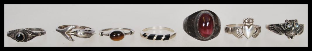 A collection of seven silver rings to include a claddagh ring, a ring in the form of a dolphin, an