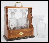 A vintage 20th century oak Tantalus with two glass decanters with geometric shaping, having a