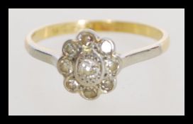 An 18ct gold and platinum diamond cluster flower head ring having a central diamond with a halo of