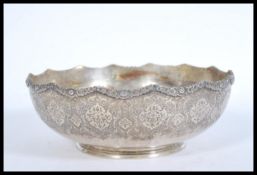 An Iranian Persian silver white metal serving bowl with an embossed floral Islamic design, shaped