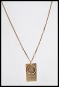 A 9ct British gold pendant necklace with a round spring clasp and inset faux coin dated 1998. The