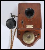 An early 20th century wall mounted telephone having an oak back and case with bakelite mouth and ear