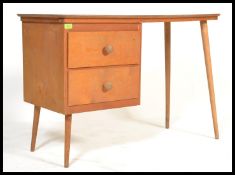 A vintage retro 20th century desk raised on tapering beech legs with red formica top above twin