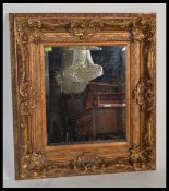 A large mirror with an ornate gold coloured frame with french rococo and baroque style detailing