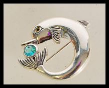 A 20th century sterling silver brooch in the form of a dolphin with an inset aqua marine stone,