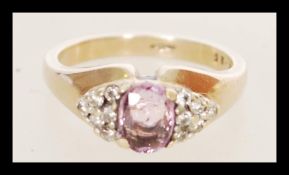 A hallmarked 9ct gold pink sapphire and diamond ring having a central pink sapphire with diamond set