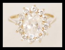 A hallmarked 9ct gold ring having a large central faceted white stone with a halo of smaller white