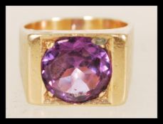 A 1970's square unmarked tests 9ct gold signet ring set with a large round cut synthetic colour