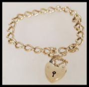 A 9ct gold 20th century bracelet with a heart padlock, safety chain and curb links. The item