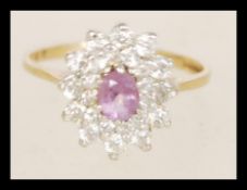A hallmarked 9ct gold cluster ring with inset cz's around a pink stone in prong settings the item