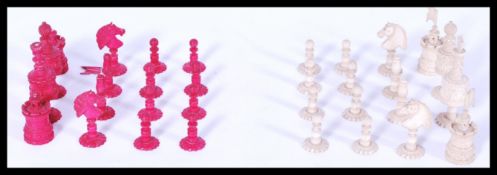 An early 20th century carved and turned bone chess set, one side stained red, the other left