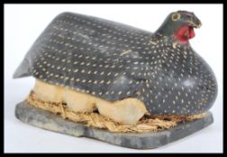 A 20th century African carved wooden folk art ornament of a nesting guineafowl with painted