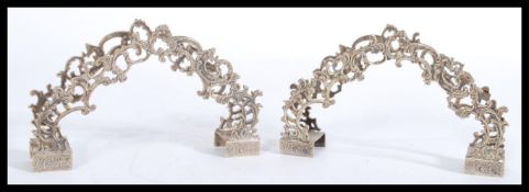 A pair of 800 silver napkin menu holders on square engraved feet with decorative scrolled leaf