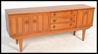 A retro 20th Century teak wood sideboard having a central bank of three drawers flanked by cupboards