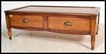 A contemporary Wesley Barrel coffee table, two drawers with lower tier magazine rack, raised on