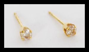 A pair of 9ct gold diamond stud earrings with prong settings. The total weight is 0.3 grams.