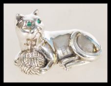 A vintage 20th century sterling silver figure of a cat with emerald eyes playing with a ball of