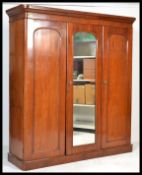 A Victorian mahogany triple wardrobe linen press compactum being raised on a plinth base having