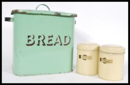 A vintage retro enamel bread bin in mint green with two enameled condiment tins reading 'coffee' and