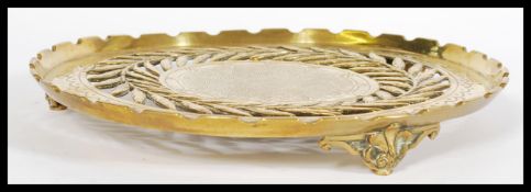 A 19th century brass tray of circular form with pierced floral detailing, raised on three scroll