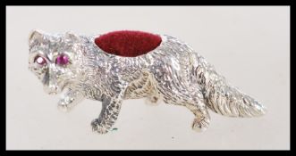 A vintage 20th century silver pin cushion model as a fox with ruby eyes and a red cushion to the