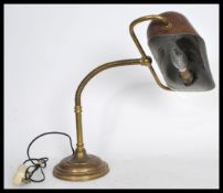 A vintage 20th century brass bankers desk lamp raised on a stepped circular base with adjustable