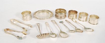 A collection of small silver wares to include a caddy spoon of shell form, a pair of sugar tongs,