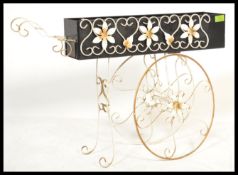 A vintage retro trolley planter with floral wire work to the top, decorative scrolled spurs to the