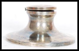 A hallmarked silver early 20th century capstan inkwell having a hinged lid on sloped circular