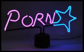 A contemporary retro style novelty neon sign table lamp raised on a circular base reading porn