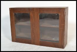 A vintage early 20th century small glazed boook case cabinet having twin glazed cupboard doors.