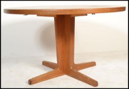 A 1970's Danish influence teak wood circular dining table being raised on twin splayed legs base