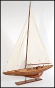 A vintage 20th century large scale wooden model of a sailing ship yacht raised on wooden stand.