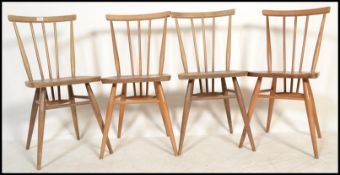 A group of four Ercol beech and elm spindle back dining chairs raised on tapered supports with