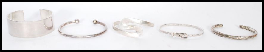 A collection of silver bangles to include a wide cuff bangle, a bangle with geometric engraving