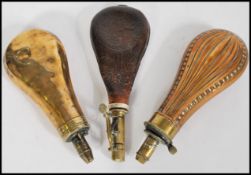 A group of three antique powder shot flasks to include a copper, brass and leather example.