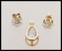 A  yellow metal pendant set with a teardrop white stone together with prong set stud earrings.