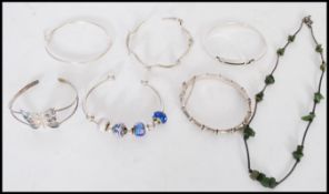 A selection of silver jewellery to include a butterfly bangle, a bamboo form bangle with hinge